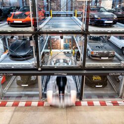 A parking system with several cars neatly lined up against a wall in the museum